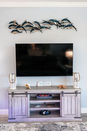 A flat-screen TV mounted on a wall above a wooden entertainment center with decorative items and a sign. - Reel It Inn is a 3/2 home in St James City. 3 kayaks,dock space, hottub, 2 bikes (Saint James City)