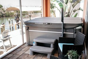 A hot tub with steps, a wicker chair, and a view of a body of water. - Reel It Inn is a 3/2 home in St James City. 3 kayaks,dock space, hottub, 2 bikes (Saint James City)