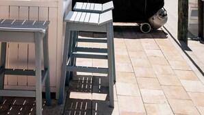 Zona de terrassa a l'aire lliure amb una barbacoa, una taula i una cadira.