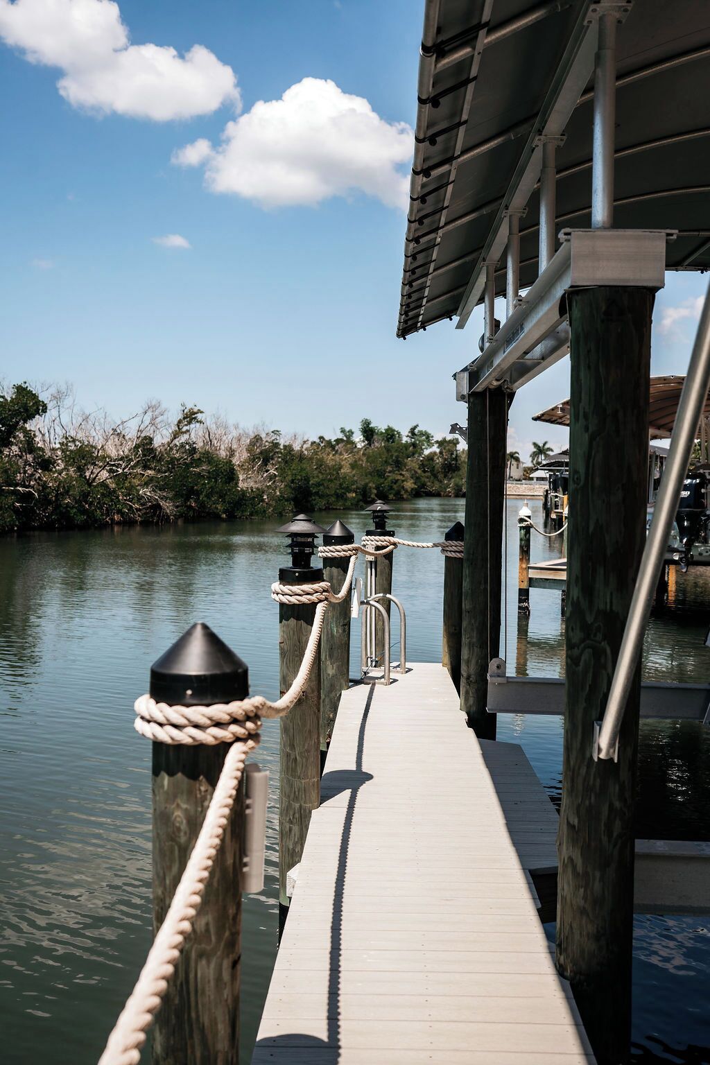 A wooden pier extending over calm water, with a metal railing and rope mooring.
