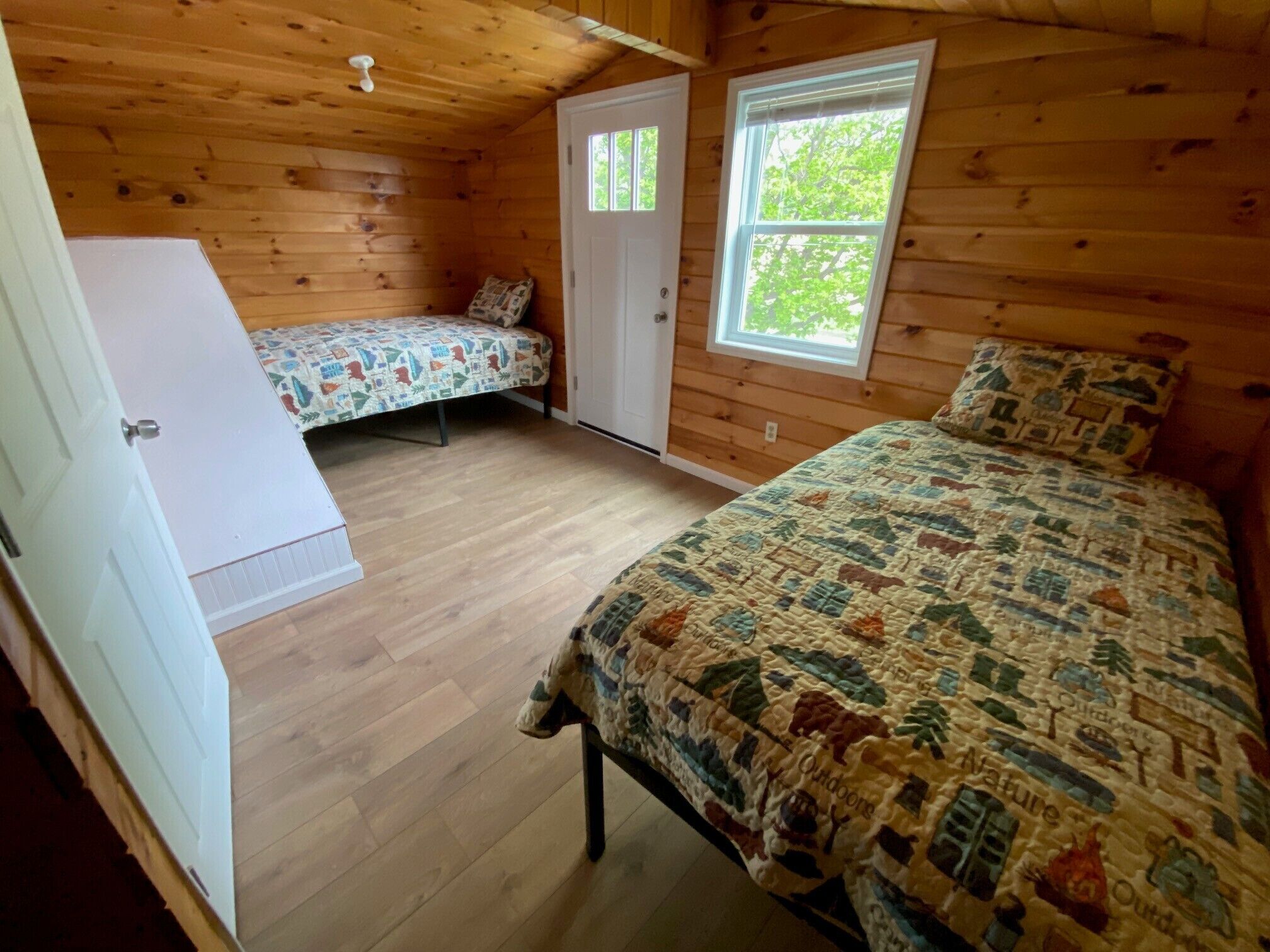 A cabin with two bedrooms, each with a bed and a window.