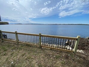 A wooden fence overlooking a calm lake with a distant shoreline.