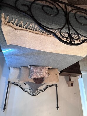 Una habitación con una cama, un cabecero de metal decorativo y una lámpara fijada a la pared.