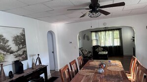 A dining area with a wooden table, chairs, and a ceiling fan.