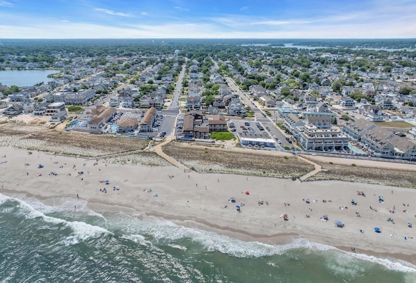 Vista aérea de un pueblo costero con playa, casas y un puerto deportivo.