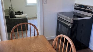Une cuisine avec une table et des chaises, un four encastré et une fenêtre.