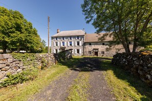 Un bâtiment en pierre avec une allée pavée menant à une porte en bois.