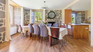 A dining area with a stone wall, wooden flooring, and a clock. - Le Domaine du Rocher - Pour 12 avec grand jardin (Neussargues-Moissac)