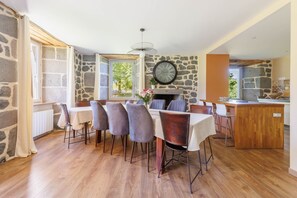 A dining area with a stone wall, wooden flooring, and a clock. - Le Domaine du Rocher - Pour 12 avec grand jardin (Neussargues-Moissac)