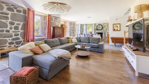 A modern living room with a sectional sofa, a glass coffee table, and a stone accent wall. - Le Domaine du Rocher - Pour 12 avec grand jardin (Neussargues-Moissac)