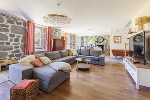 A modern living room with a sectional sofa, a glass coffee table, and a stone accent wall. - Le Domaine du Rocher - Pour 12 avec grand jardin (Neussargues-Moissac)