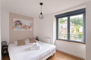 Ein Schlafzimmer mit einem Bett, einem Heizkörper, einem Fenster mit Blick und einer Pendelleuchte.