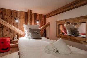 A bedroom with a wooden ceiling, a bed with white bedding, a red basket, and a small deer figurine. - Cabane Malou avec jardin et à  200m des pistes (La Salle-les-Alpes)