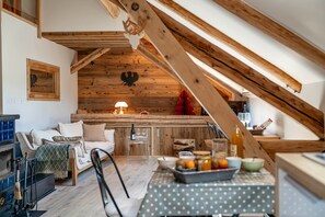A loft-style room with a wooden ceiling, a dining table with a polka dot tablecloth, a sofa, and a small kitchen area. - Cabane Malou avec jardin et à  200m des pistes (La Salle-les-Alpes)