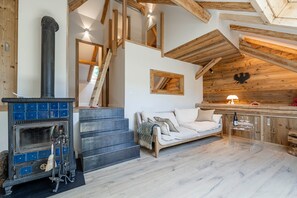 A rustic interior with a fireplace, wooden beams, a sofa, and a staircase. - Cabane Malou avec jardin et à  200m des pistes (La Salle-les-Alpes)