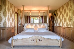 Un grand lit avec une tête de lit en bois, un miroir au-dessus et un papier peint à motifs.