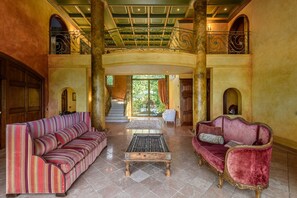 Eine großzügige Lobby mit hoher Decke, einer zentralen Treppe und zwei Sofas.