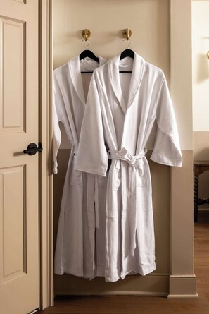 Two white robes hanging on a door.