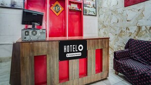 Ein Hotelrezeptionstresen mit einer Uhr, gerahmten Bildern und einer roten Wand.