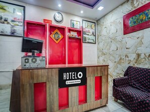 Ein Hotelrezeptionstresen mit einer Uhr, gerahmten Bildern und einer roten Wand.