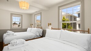 A hotel room with two beds, large windows, and a hanging light fixture.