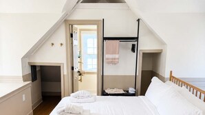 Ein Schlafzimmer mit einem hölzernen Bett, einem Schreibtisch und einem begehbaren Kleiderschrank.