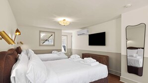 Hotellihuone, jossa on kaksi sänkyä, televisio, ilmastointilaite ja suuri peili.