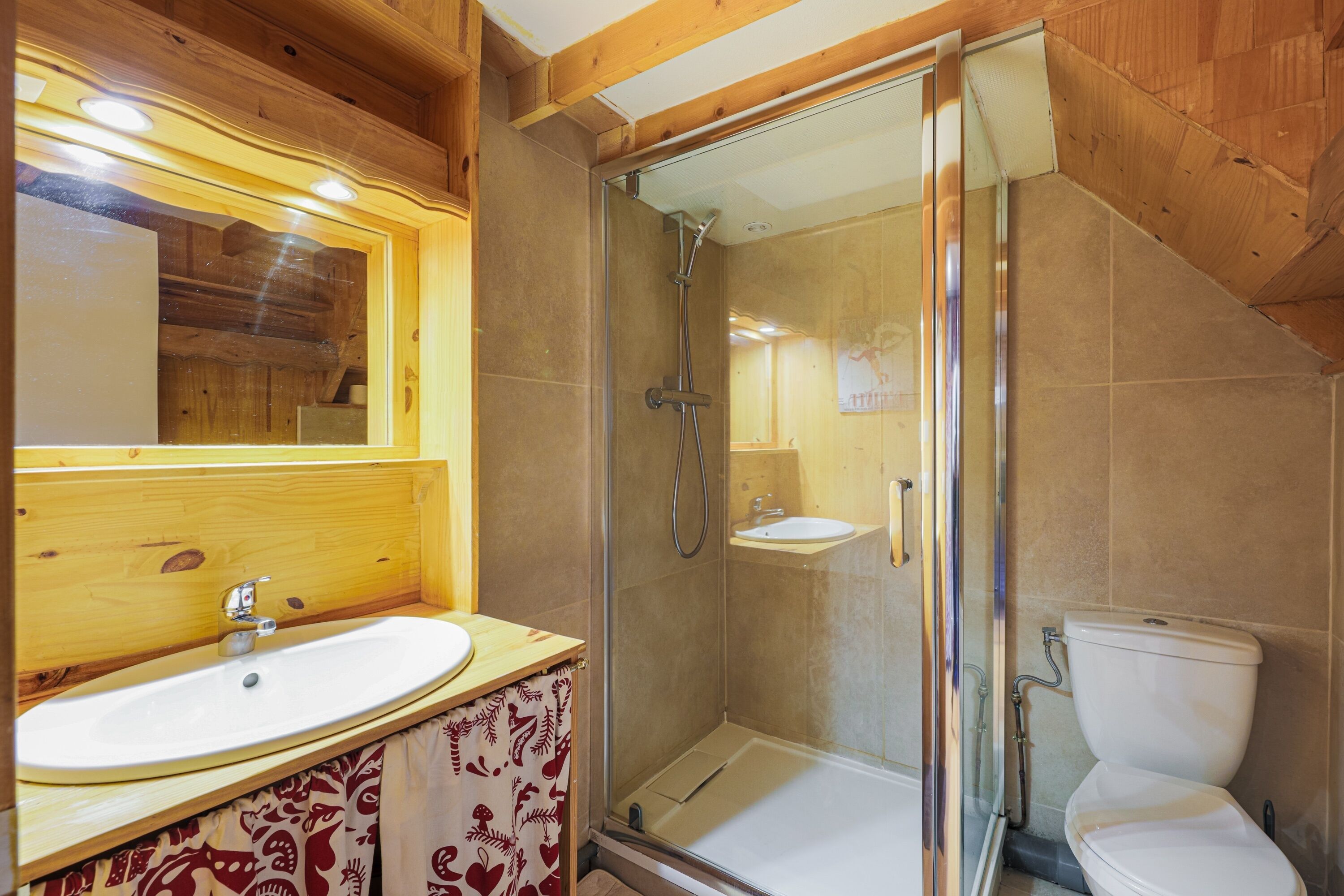 A bathroom with a wooden vanity, a glass shower enclosure, and a toilet.