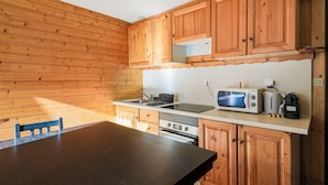 A kitchen with wooden cabinets, a countertop, a sink, a stove, and a microwave. - Le Pré de l'Arche - À 400 m des télécabines (Oz)