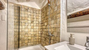 Un bagno con doccia vetrata, un lavandino bianco e un mobile vanitario in legno.