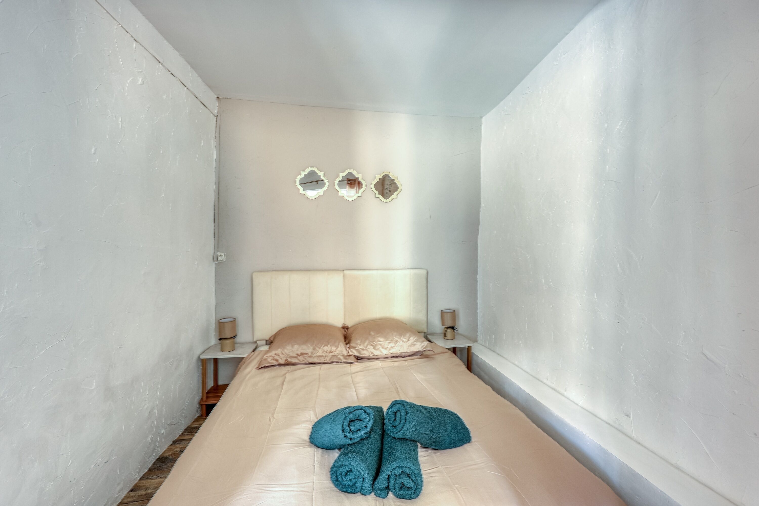 Un letto singolo con testiera, due comodini e tre specchi a parete.