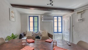 Zona pranzo con tavolo in legno, sedie, divano e una pianta in vaso.