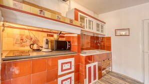 Una cucina con piastrelle arancioni, un forno a microonde, un bollitore e un lavandino.