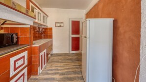 Una cucina piccola con frigorifero, mobili e zoccolo in piastrelle.