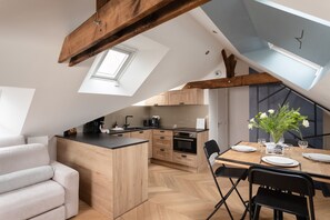 Eine moderne Küche mit Holzausstattung, einem Esstisch für zwei Personen und einer erhöhten Schlafkoje.