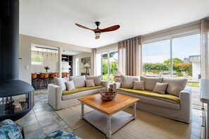 A modern living room with a fireplace, a sofa set, a coffee table, and a view of the outdoors. - Les Volets Bleus de Rhuys - Avec piscine privée (Saint-Gildas-de-Rhuys)