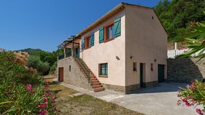 A two-story building with a stone base, a flat roof, and a staircase leading to the upper floor. - Le Nid de Ciambonson - Terrasse avec vue montagne (La Tour)