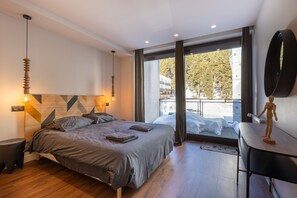 Ein modernes Schlafzimmer mit Bett, Nachttischen, einem Schreibtisch und einem großen Fenster mit Blick.