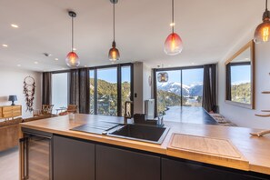 Eine moderne Küche mit einer großen Kochinsel, einem Spülbecken und Pendelleuchten.