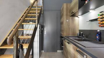 Cozinha moderna com escada de madeira, eletrodomésticos embutidos e bancada preta.