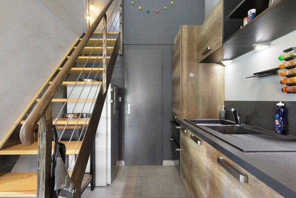 A modern kitchen with a wooden staircase, built-in appliances, and a black countertop.