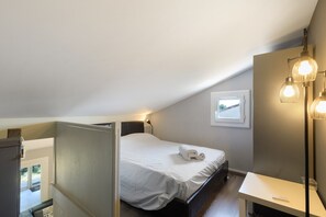 Un dormitorio con cama, mesita de noche, lámpara y ventana con vistas.