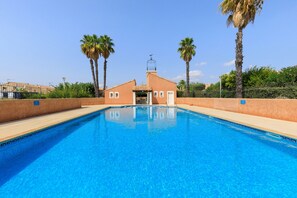 A swimming pool with a building in the background, surrounded by palm trees.