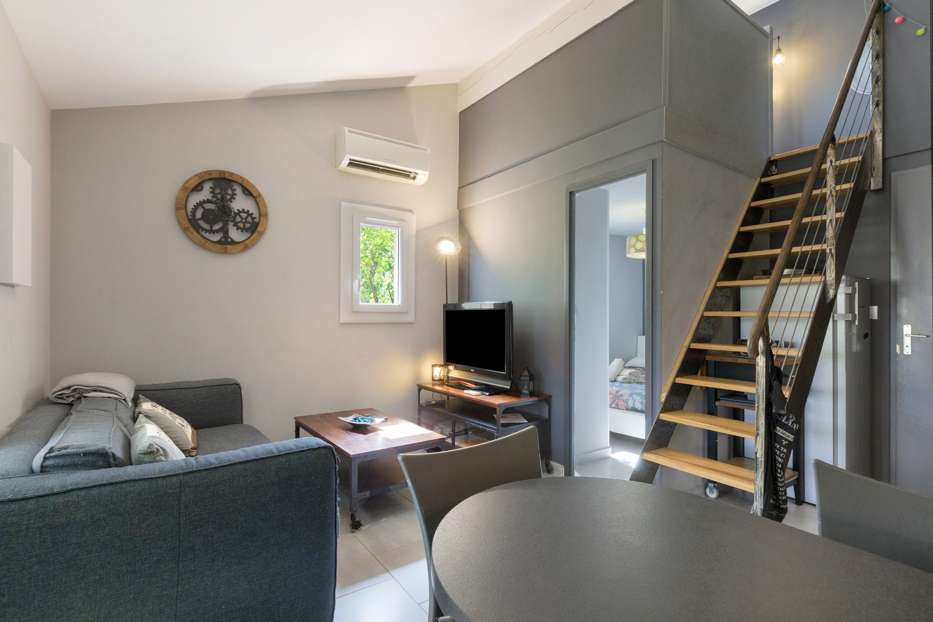 Ein modernes Wohnzimmer mit Sofa, Tisch, Fernseher und einer Treppe.