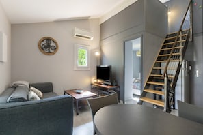 A modern living room with a sofa, a table, a TV, and a staircase.