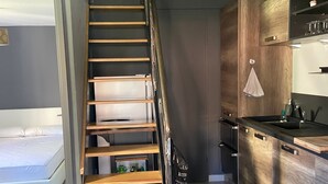 A modern kitchen with wooden cabinets, a built-in stove, and a small dining area.