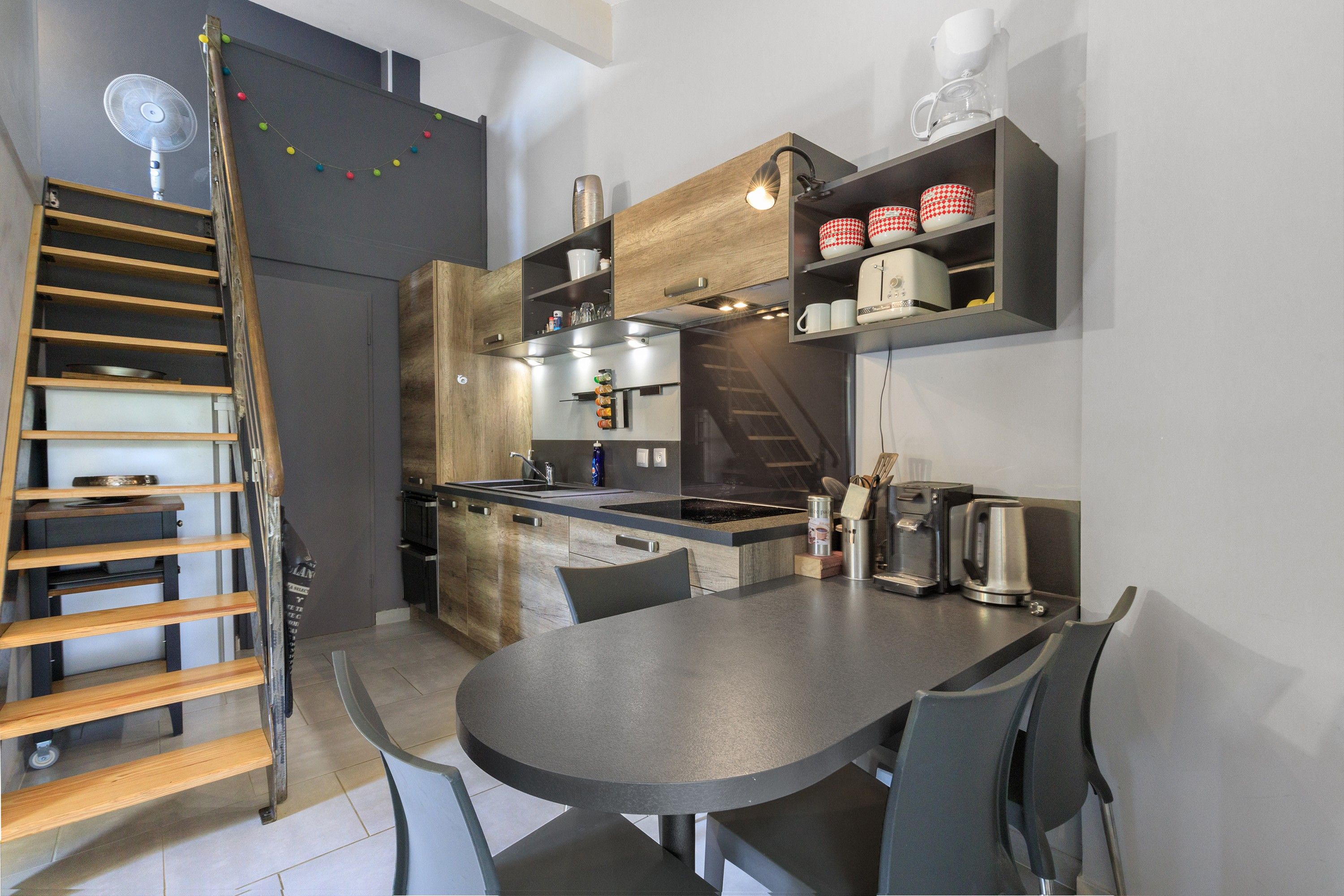 Een moderne keuken met een centraal eiland, inbouwapparatuur en een eethoek met een ronde tafel en stoelen.