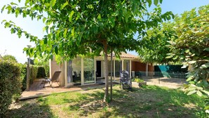 A house with a glass door entrance, a patio with a chair, and a fenced garden area.