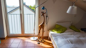A bedroom with a bed, a standing lamp, and a giraffe statue.