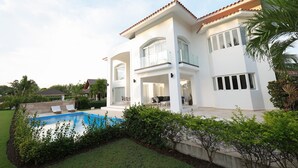 Ein modernes, zweistöckiges Haus mit Swimmingpool, Sitzgelegenheit im Freien und einem gepflegten Garten.